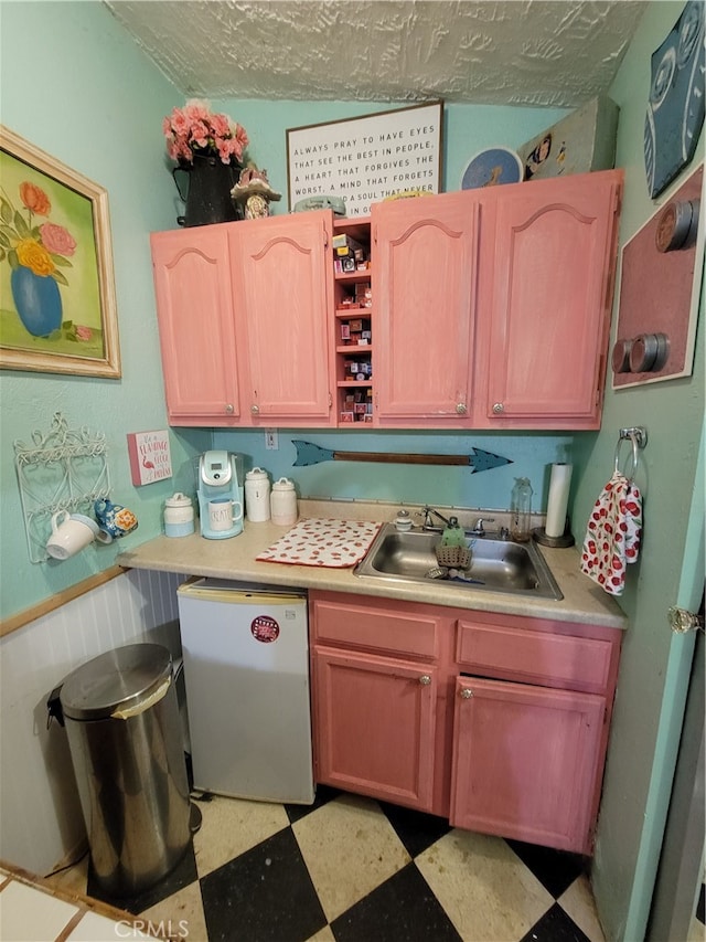 kitchen featuring light tile patterned flooring, fridge, and sink