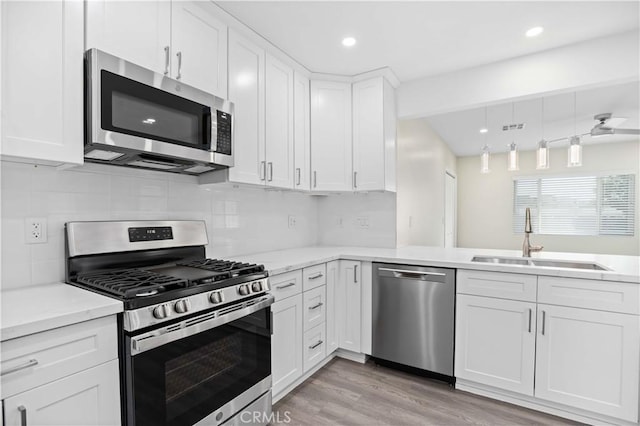 kitchen featuring white cabinetry, sink, stainless steel appliances, light hardwood / wood-style floors, and decorative backsplash