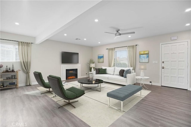 living room featuring beamed ceiling, light wood-type flooring, and ceiling fan