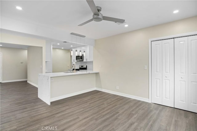 unfurnished living room with dark hardwood / wood-style flooring, ceiling fan, and sink