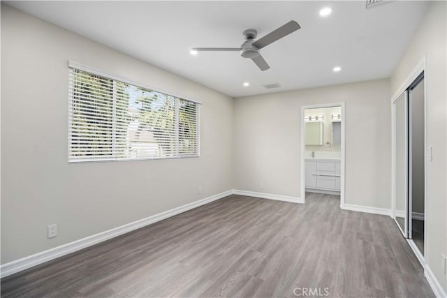 unfurnished bedroom with ceiling fan, light hardwood / wood-style floors, ensuite bath, and a closet