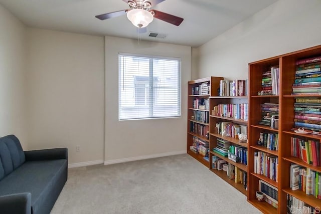 living area featuring light carpet, baseboards, visible vents, and a ceiling fan