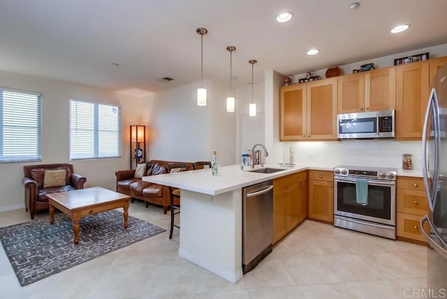 kitchen featuring pendant lighting, light countertops, appliances with stainless steel finishes, open floor plan, and a peninsula