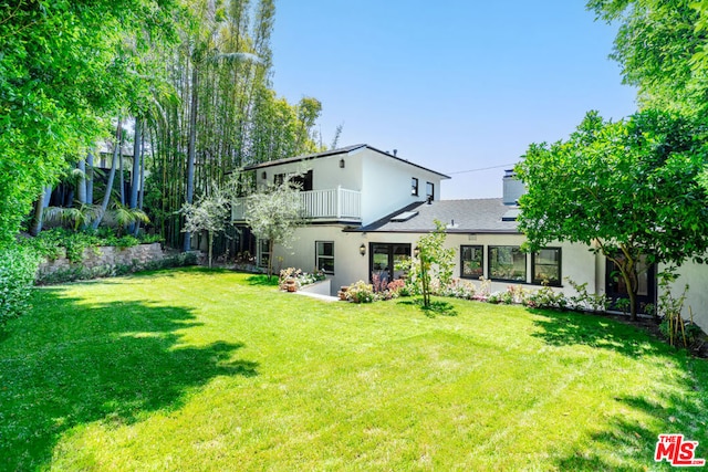 back of house with a yard and a balcony