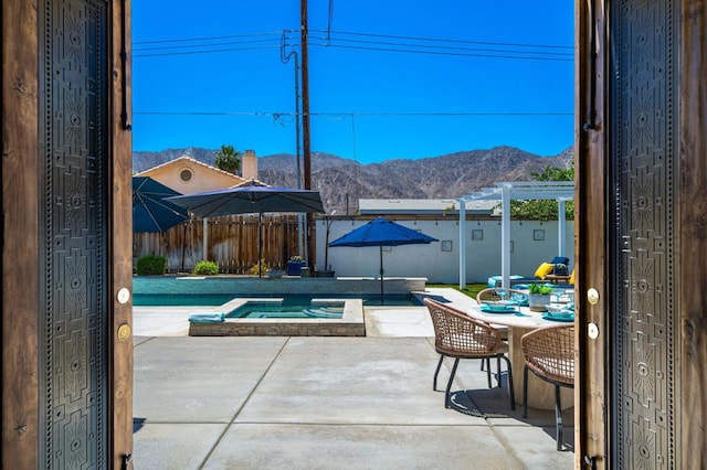 view of patio featuring a pergola, a mountain view, and an in ground hot tub