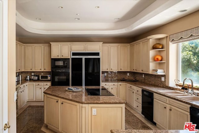 kitchen featuring a raised ceiling, black appliances, a center island, cream cabinets, and sink