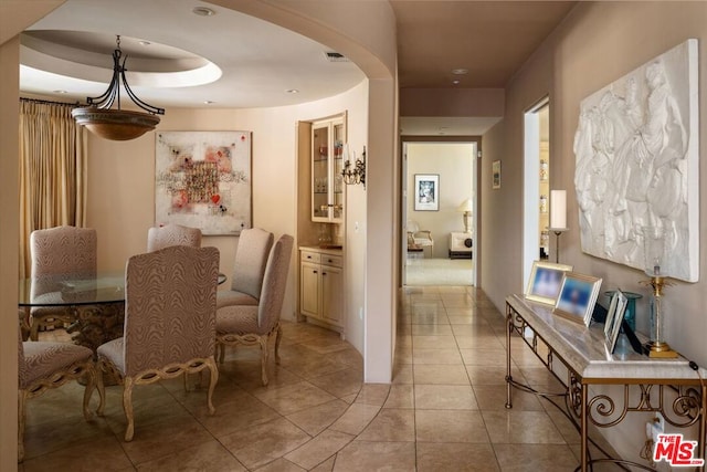 tiled dining area with a raised ceiling