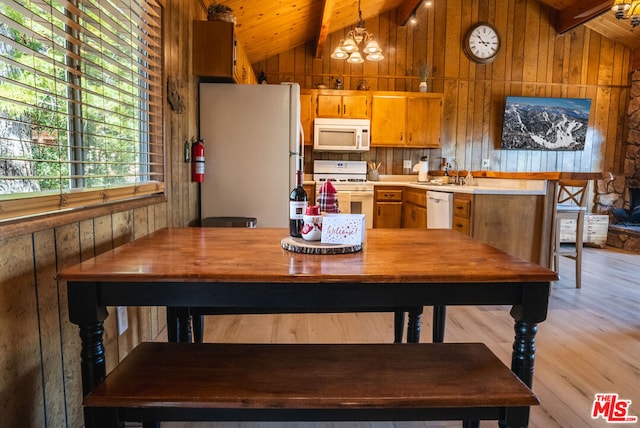 kitchen featuring light hardwood / wood-style flooring, lofted ceiling with beams, a notable chandelier, white appliances, and wooden walls