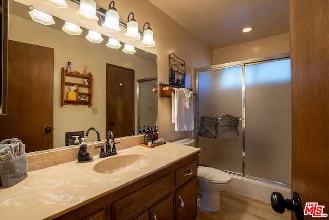 bathroom featuring vanity, toilet, an enclosed shower, and wood-type flooring