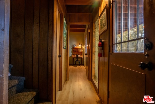 hallway with wood walls and light wood-type flooring