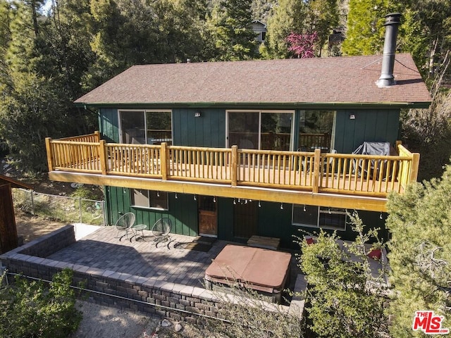 back of property with a patio, a wooden deck, and a hot tub