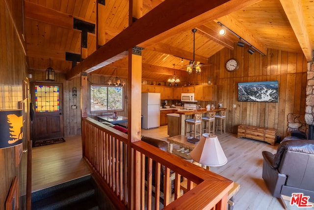 living room featuring a chandelier, lofted ceiling with beams, light hardwood / wood-style flooring, and wooden walls