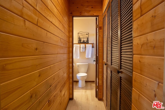 bathroom with wood-type flooring, toilet, and wood walls