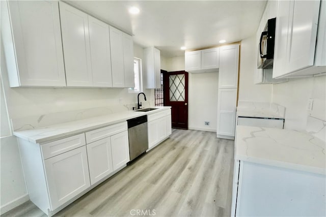 kitchen with stainless steel appliances, white cabinetry, light stone countertops, light wood-type flooring, and sink