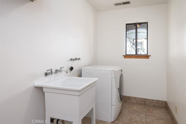 clothes washing area with laundry area, washer / dryer, baseboards, visible vents, and a sink