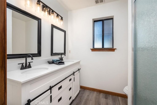 full bathroom featuring double vanity, wood finished floors, a sink, and baseboards