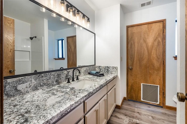 full bathroom with baseboards, visible vents, a shower, wood finished floors, and vanity