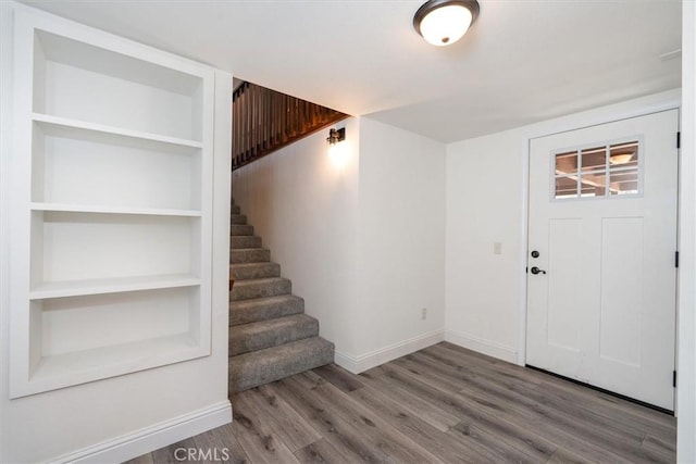 foyer entrance with stairs, baseboards, and wood finished floors