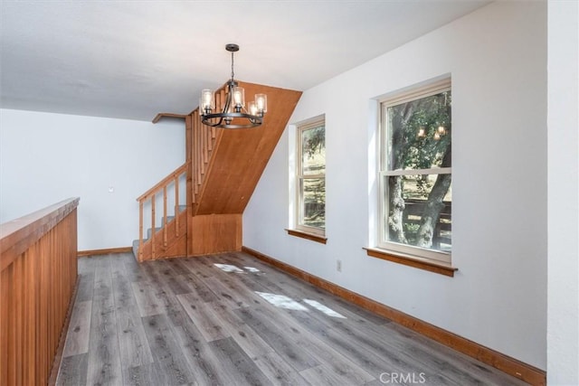 bonus room featuring wood finished floors, stairway, baseboards, and an inviting chandelier