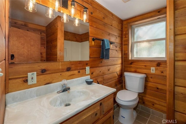 bathroom with toilet, tile patterned flooring, wooden walls, and vanity