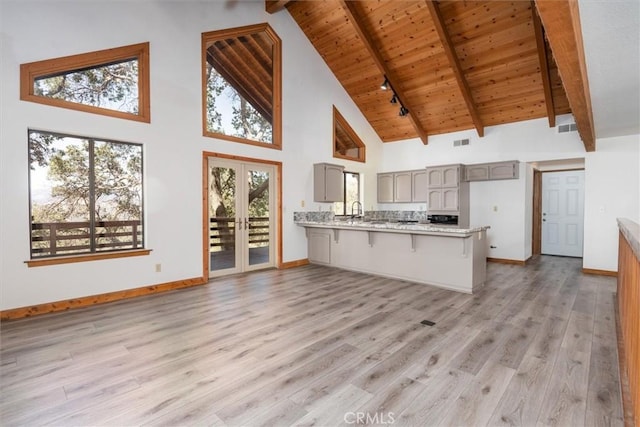 kitchen with a peninsula, gray cabinets, beam ceiling, and french doors