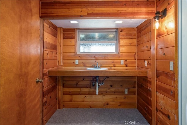 bathroom featuring wooden walls and a sink