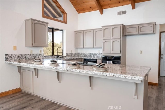 kitchen featuring visible vents, wooden ceiling, a peninsula, beam ceiling, and black oven