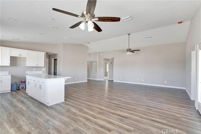 kitchen featuring white cabinets, light hardwood / wood-style flooring, and lofted ceiling