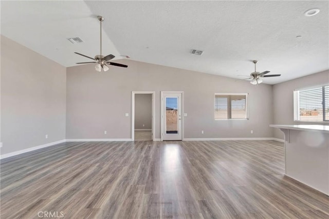 unfurnished living room featuring hardwood / wood-style floors, a textured ceiling, ceiling fan, and lofted ceiling