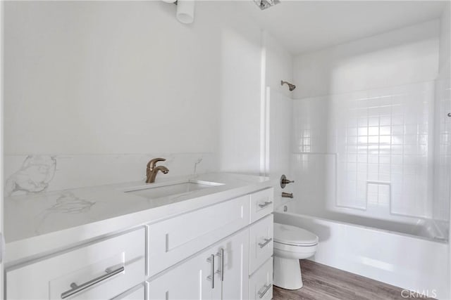 full bathroom featuring tiled shower / bath combo, toilet, wood-type flooring, and vanity