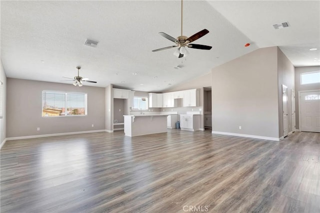 unfurnished living room featuring hardwood / wood-style floors, ceiling fan, and high vaulted ceiling