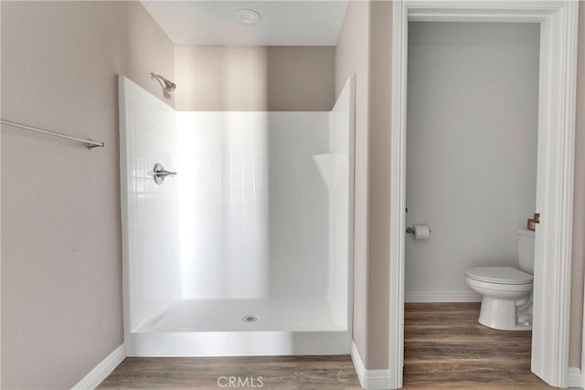 bathroom featuring a shower, hardwood / wood-style floors, and toilet