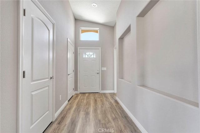 doorway featuring light hardwood / wood-style flooring and vaulted ceiling