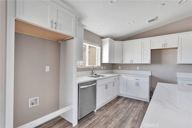 kitchen with hardwood / wood-style floors, white cabinets, sink, vaulted ceiling, and stainless steel dishwasher