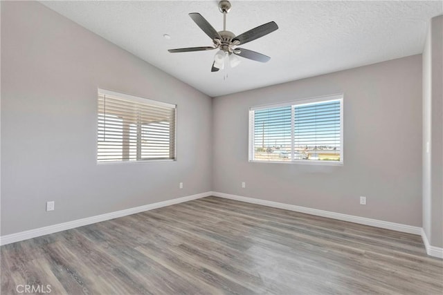 empty room with a textured ceiling, ceiling fan, hardwood / wood-style floors, and vaulted ceiling