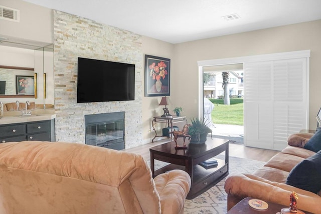 living room featuring a stone fireplace and light hardwood / wood-style floors