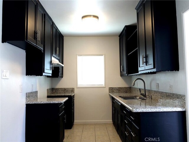 kitchen with light tile patterned floors, sink, and light stone counters