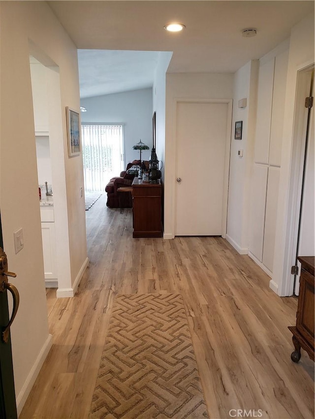 hallway featuring light hardwood / wood-style floors and vaulted ceiling