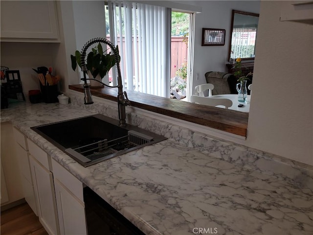 kitchen featuring white cabinetry, sink, and light stone counters