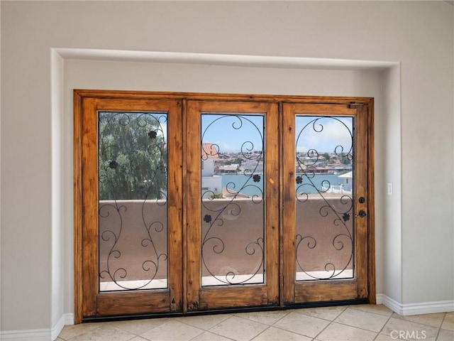 doorway featuring light tile patterned floors, french doors, and baseboards