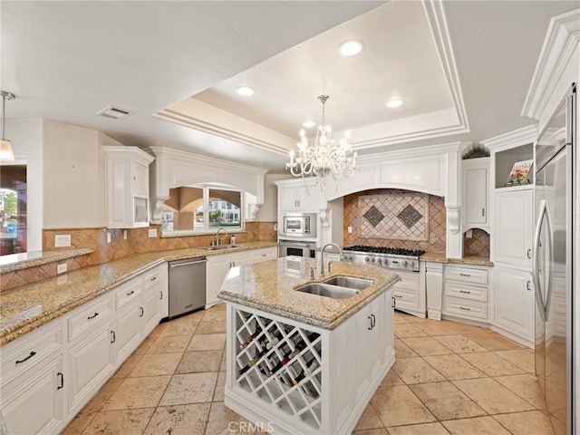 kitchen with a raised ceiling, built in appliances, and a sink