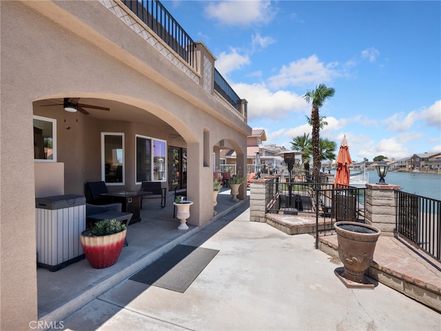 view of patio featuring a water view, ceiling fan, and a balcony