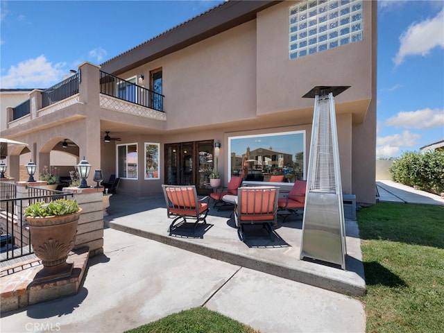 back of property with a balcony, an outdoor fire pit, and a patio