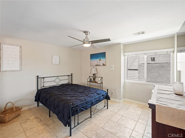 bedroom with stone tile flooring, visible vents, a ceiling fan, and baseboards