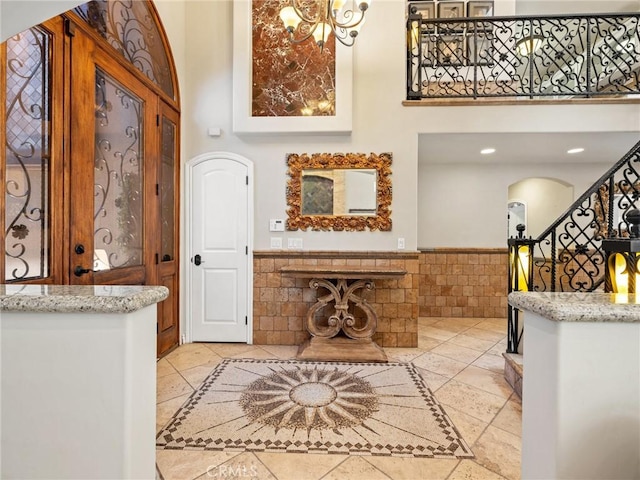 entrance foyer with stairway, arched walkways, tile walls, a fireplace, and wainscoting