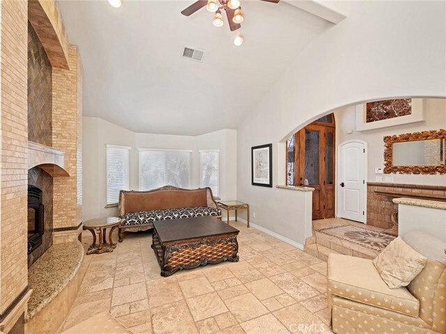 living room featuring high vaulted ceiling, ceiling fan, beamed ceiling, and a brick fireplace