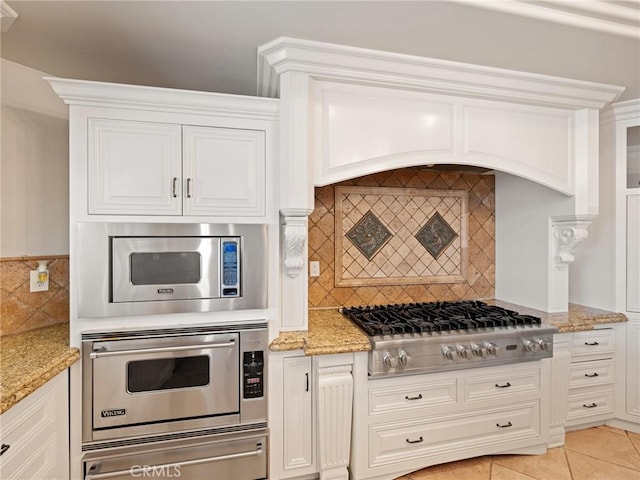 kitchen with backsplash, light tile patterned floors, stainless steel appliances, white cabinetry, and a warming drawer