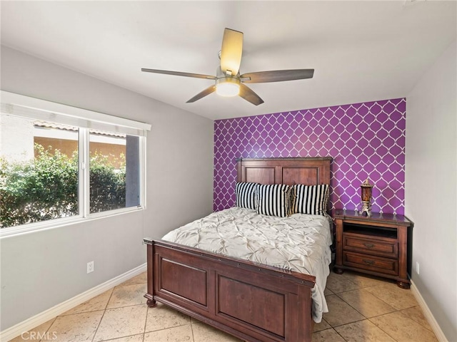 bedroom featuring an accent wall, baseboards, and ceiling fan