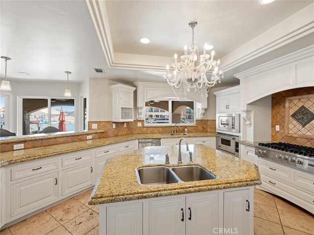 kitchen featuring hanging light fixtures, appliances with stainless steel finishes, sink, decorative backsplash, and a kitchen island with sink