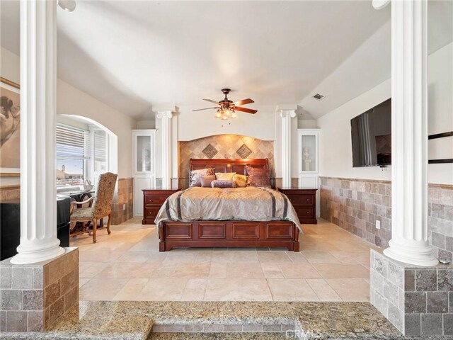 bedroom featuring lofted ceiling, tile walls, ceiling fan, and ornate columns